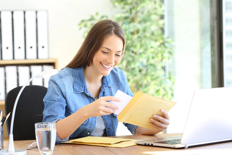 Happy entrepreneur putting document in an envelope working at office Happy entrepreneur putting document in an envelope working at office