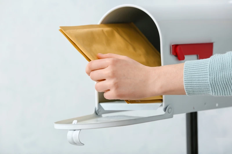 Woman getting letters from box on light background Woman getting letters from box on light background